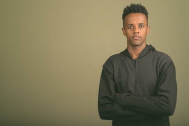 Renkli arka planda siyah kapüşonlu genç Afrikalı adamın stüdyo fotoğrafı.