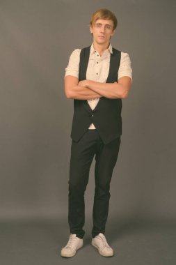 Stüdyo fotoğrafı, sarı saçlı, gri arka planda genç ve yakışıklı iş adamı.