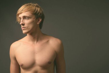 Sarışın, üstsüz, yakışıklı bir adamın stüdyo fotoğrafı.