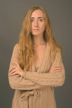 Stüdyo resmi, sarı saçlı, gri arka planda kalın kıyafetler giyen güzel bir kadın.