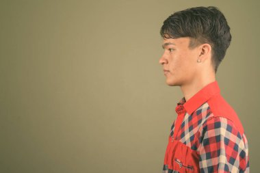 Renkli arka planda kırmızı kareli gömlek giyen genç Hintli adamın stüdyo fotoğrafı.