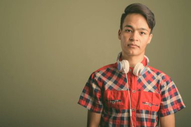 Renkli arka planda kırmızı kareli gömlek giyen genç Hintli adamın stüdyo fotoğrafı.