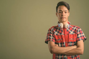 Renkli arka planda kırmızı kareli gömlek giyen genç Hintli adamın stüdyo fotoğrafı.