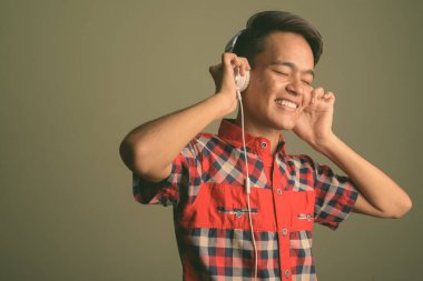 Renkli arka planda kırmızı kareli gömlek giyen genç Hintli adamın stüdyo fotoğrafı.