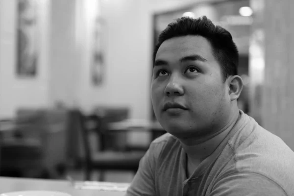 Молодий чоловік з надмірною вагою, азіат, думає у кав "ярні. — стокове фото
