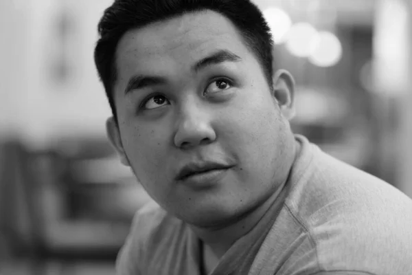 Ansikte på ung överviktig asiatisk man tänker på kaféet — Stockfoto