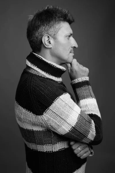 Studio shot of man with blond hair wearing turtleneck sweater against gray background in black and white