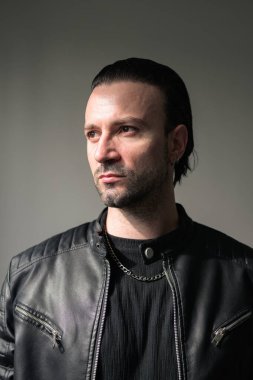 Siyah deri ceket giyen kendine güvenen sakallı adam.