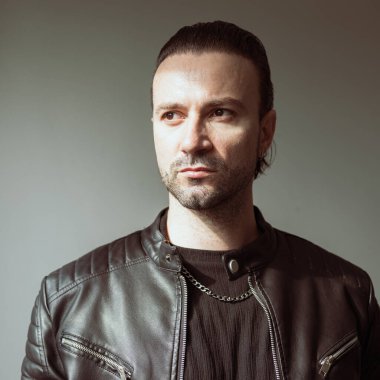 Siyah deri ceket giyen kendine güvenen sakallı adam.