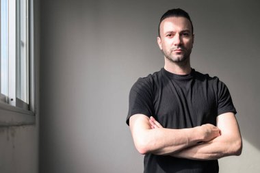 Siyah tişörtlü, sakallı yakışıklı bir adamın portresi.