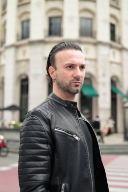 Siyah deri ceket giyen kendine güvenen sakallı adam.