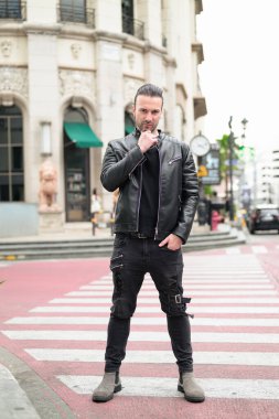 Siyah deri ceket giyen kendine güvenen sakallı adam.