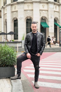 Siyah deri ceket giyen kendine güvenen sakallı adam.