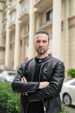 Siyah deri ceket giyen kendine güvenen sakallı adam.