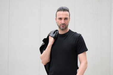 Siyah deri ceket giyen kendine güvenen sakallı adam.