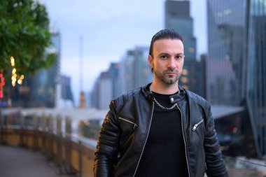 Çatıda siyah deri ceket giyen yakışıklı bir adam.