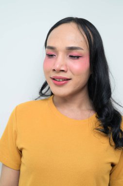 Makyajlı ve uzun saçlı Taylandlı genç bir transseksüelin stüdyo portresi. Cinsiyet ifadesi kavramı, LGBTQ gururu ve özgün güzellik ve çeşitliliği gösteren kapsayıcılık.