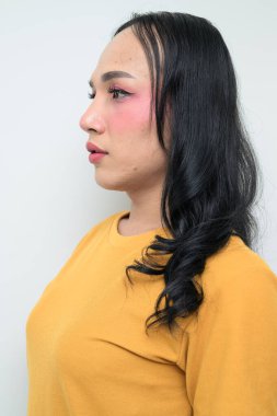 Makyajlı ve uzun saçlı Taylandlı genç bir transseksüelin stüdyo portresi. Cinsiyet ifadesi kavramı, LGBTQ gururu ve özgün güzellik ve çeşitliliği gösteren kapsayıcılık.