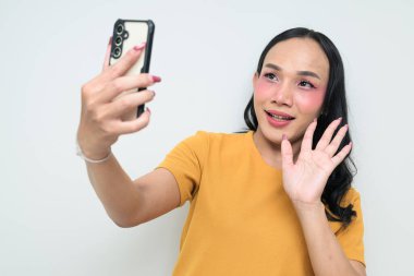Telefon kullanarak uzun saçlı, makyajlı Taylandlı genç bir transseksüelin stüdyo portresi. Cinsiyet ifadesi kavramı, LGBTQ gururu ve özgün güzellik ve çeşitliliği gösteren kapsayıcılık.
