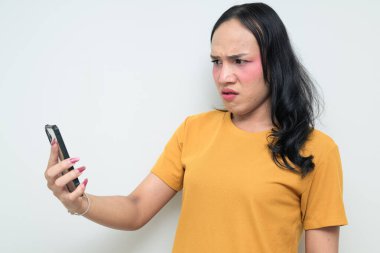 Telefon kullanarak uzun saçlı, makyajlı Taylandlı genç bir transseksüelin stüdyo portresi. Cinsiyet ifadesi kavramı, LGBTQ gururu ve özgün güzellik ve çeşitliliği gösteren kapsayıcılık.