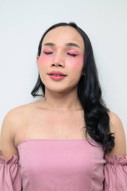 Makyajlı ve uzun saçlı Taylandlı genç bir transseksüelin stüdyo portresi. Cinsiyet ifadesi kavramı, LGBTQ gururu ve özgün güzellik ve çeşitliliği gösteren kapsayıcılık.