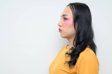 Makyajlı ve uzun saçlı Taylandlı genç bir transseksüelin stüdyo portresi. Cinsiyet ifadesi kavramı, LGBTQ gururu ve özgün güzellik ve çeşitliliği gösteren kapsayıcılık.