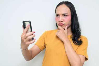 Telefon kullanarak uzun saçlı, makyajlı Taylandlı genç bir transseksüelin stüdyo portresi. Cinsiyet ifadesi kavramı, LGBTQ gururu ve özgün güzellik ve çeşitliliği gösteren kapsayıcılık.