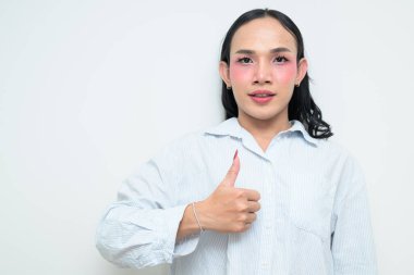 Makyajlı ve uzun saçlı Taylandlı genç bir transseksüelin stüdyo portresi. Cinsiyet ifadesi kavramı, LGBTQ gururu ve özgün güzellik ve çeşitliliği gösteren kapsayıcılık.