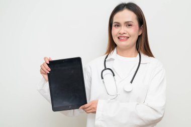 Tablet bilgisayar kullanan, beyaz önlük ve steteskop giyen Asyalı bir sağlık uzmanının stüdyo portresi. Tıbbi, hastane, klinik ve sağlık konularına uygun kavram.