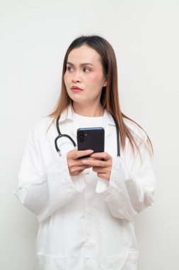 Beyaz önlük giyen ve steteskop kullanan Asyalı bir sağlık uzmanının stüdyo portresi. Tıbbi, hastane, klinik ve sağlık konularına uygun kavram.