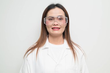 Beyaz önlük ve koruyucu gözlük takan Asyalı bir bilim adamının stüdyo portresi. Laboratuvar, araştırma, bilim, tıp ve klinik temalar için ciddi ve profesyonel görünüm uygun.