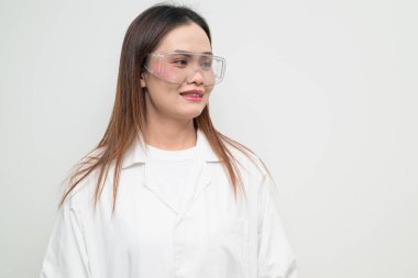 Beyaz önlük ve koruyucu gözlük takan Asyalı bir bilim adamının stüdyo portresi. Laboratuvar, araştırma, bilim, tıp ve klinik temalar için ciddi ve profesyonel görünüm uygun.