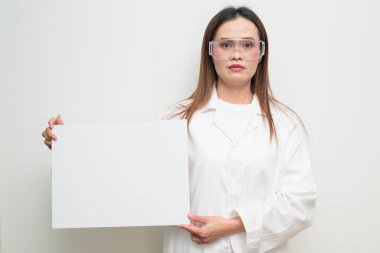 Beyaz önlük ve koruyucu gözlük takan Asyalı bir bilim adamının stüdyo portresi. Laboratuvar, araştırma, bilim, tıp ve klinik temalar için ciddi ve profesyonel görünüm uygun.