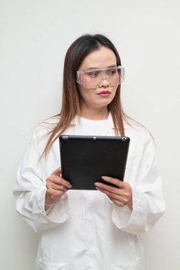 Beyaz önlük ve koruyucu gözlük takan Asyalı bir bilim adamının stüdyo portresi. Laboratuvar, araştırma, bilim, tıp ve klinik temalar için ciddi ve profesyonel görünüm uygun.