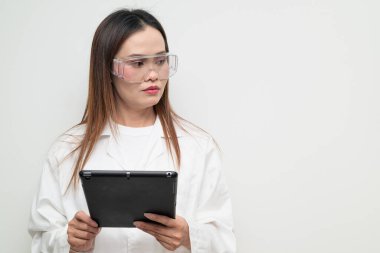 Beyaz önlük ve koruyucu gözlük takan Asyalı bir bilim adamının stüdyo portresi. Laboratuvar, araştırma, bilim, tıp ve klinik temalar için ciddi ve profesyonel görünüm uygun.