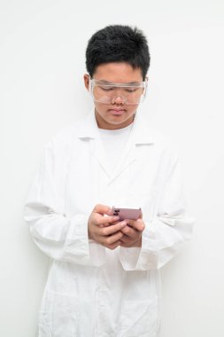 Beyaz laboratuvar önlüğü ve koruyucu gözlük takan Asyalı bir çocuğun portresi. Sağlık hizmetleri, tıp eğitimi, çocuk mesleği hayalleri ve gelecekteki bilim adamı kavramları için uygundur..