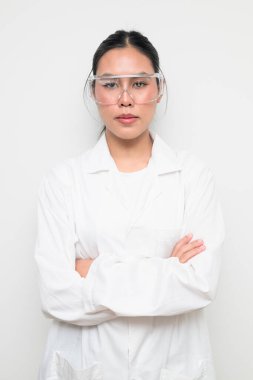 Koruyucu gözlük takan kadın bir bilim adamının portresi ve temiz bir stüdyo geçmişine sahip beyaz bir laboratuvar önlüğü. Bilim, laboratuvar çalışmaları, araştırma, güvenlik ve STEM temaları için elverişli.