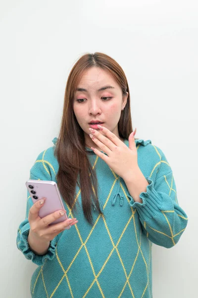 Genç Asyalı bir kadının cep telefonuyla beyaz arkaplan üzerindeki stüdyo portresi