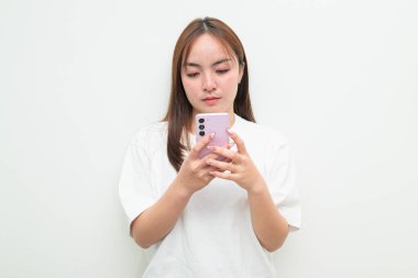 Studio portrait of a young Asian woman against white background using phone
