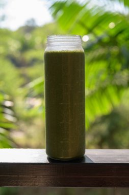 Tropikal yapraklı yeşil meyve suyu, sağlıklı vejetaryen yaşam tarzını ve doğal beslenmeyi temsil ediyor.