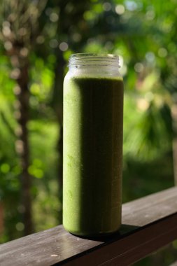 Tropikal yapraklı yeşil meyve suyu, sağlıklı vejetaryen yaşam tarzını ve doğal beslenmeyi temsil ediyor.