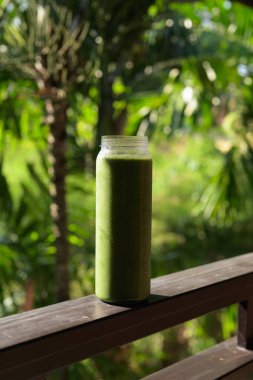 Tropikal yapraklı yeşil meyve suyu, sağlıklı vejetaryen yaşam tarzını ve doğal beslenmeyi temsil ediyor.