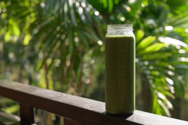 Tropikal yapraklı yeşil meyve suyu, sağlıklı vejetaryen yaşam tarzını ve doğal beslenmeyi temsil ediyor.