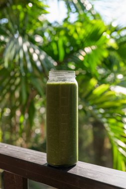 Tropikal yapraklı yeşil meyve suyu, sağlıklı vejetaryen yaşam tarzını ve doğal beslenmeyi temsil ediyor.