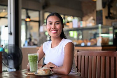 Gülümseyen Asyalı Kadın Buzlu Matcha Latte içiyor Cafe with Tatlıyla