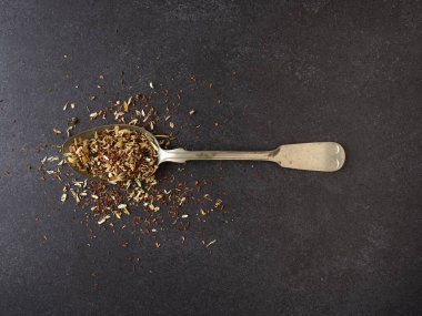 Kırsal bir kaşıkta organik çay karışımı, metin için alanı olan koyu taş arkaplan