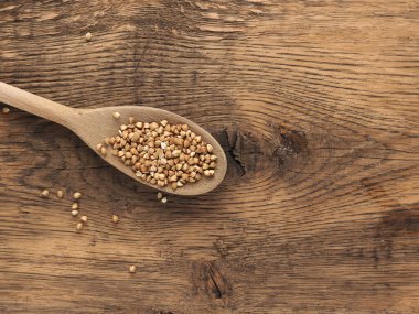 Tahta mutfak masasında tahta kaşık üzerinde karabuğday, yazı için yer var, sağlıklı yiyecek kavramı.