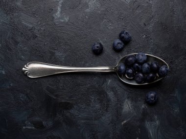 Siyah arka planda gümüş kaşıkta taze organik yaban mersini, süper yiyecek, sağlıklı beslenme, antioksidan.