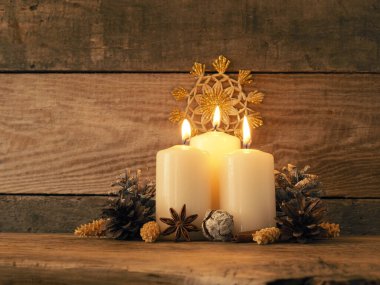 Üçüncü Advent, üç mum Noel süslemesi ile birlikte ahşap bir masada yanıyor.