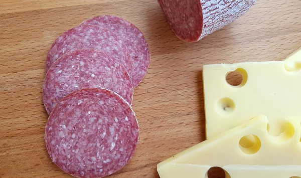 Сыр и салями на деревянном столе — стоковое фото